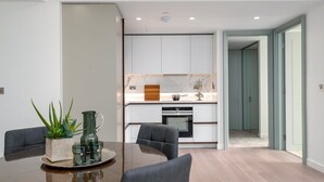 A modern kitchen with white cabinets, a marble backsplash, and a central island. - GuestReady - 2BR Luxury Flat in Central London (London)