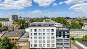 A multi-story building with a flat roof and large windows, surrounded by other buildings and trees. - GuestReady Essential - Penthouse Vibes in Peckham (London)