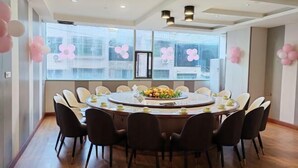 Un salón de conferencias con una mesa redonda, sillas negras y un centro de mesa floral.
