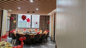 Un salón de conferencias con una mesa redonda, sillas negras y globos rojos.