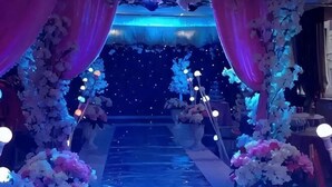 Un pasillo decorado con arreglos florales y telas colgantes.