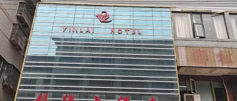 A hotel with a modern facade, a prominent logo, and a sign in a foreign language.