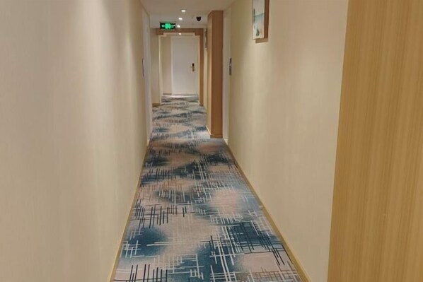 A hallway with patterned carpet, beige walls, and wooden paneling. - Yinlai Hotel (Xuanhan)