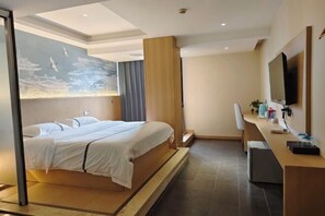 Una habitación de hotel moderna con una cama grande, un escritorio y un televisor de pantalla plana.