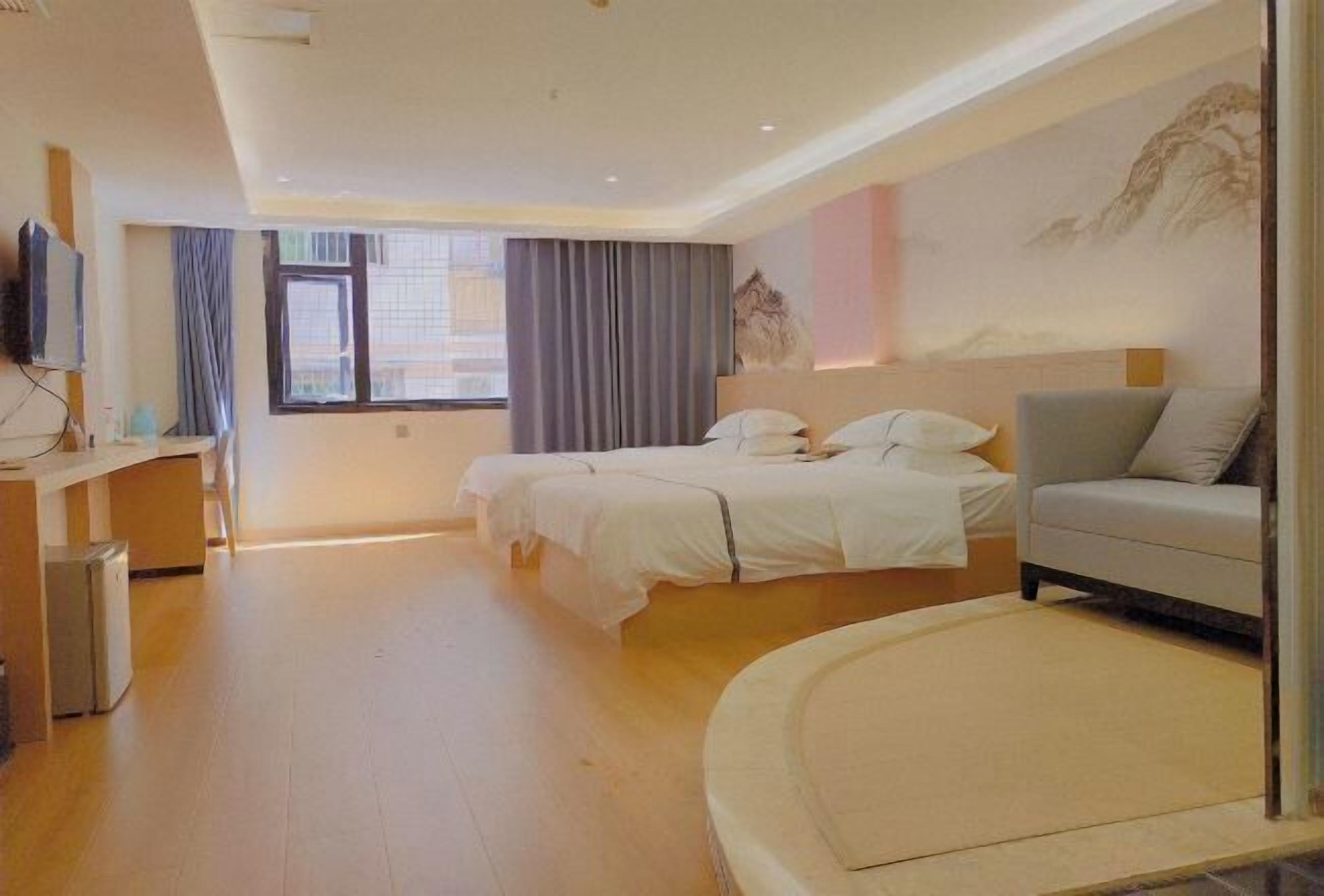 A hotel room with a bed, a sofa, a TV, and a desk.