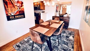 Ein Essbereich mit Holztisch, Stühlen, einer Chandelier und einem Teppich.