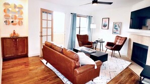 Ein Wohnzimmer mit braunem Ledersofa, einem Couchtisch, einem Kamin und einem Deckenventilator.