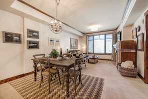 A dining area with a wooden table and chairs, a chandelier, and artwork on the walls.