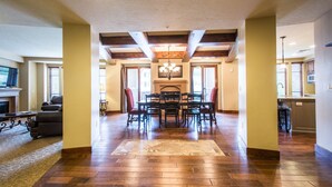Un salón amplio con chimenea, piso de madera y un comedor con sillas.