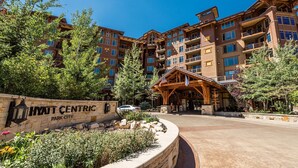 Un hotel de varios pisos con fachada de piedra, un pabellón de entrada de madera y un letrero que dice "HYATT CENTRIC PARK CITY".