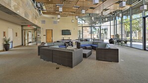 A spacious lobby with a high ceiling, modern furniture, and large windows offering views of the outdoors. - Modern Irvine Condo w/ Pool - 7 Mi to Beach! (Irvine)