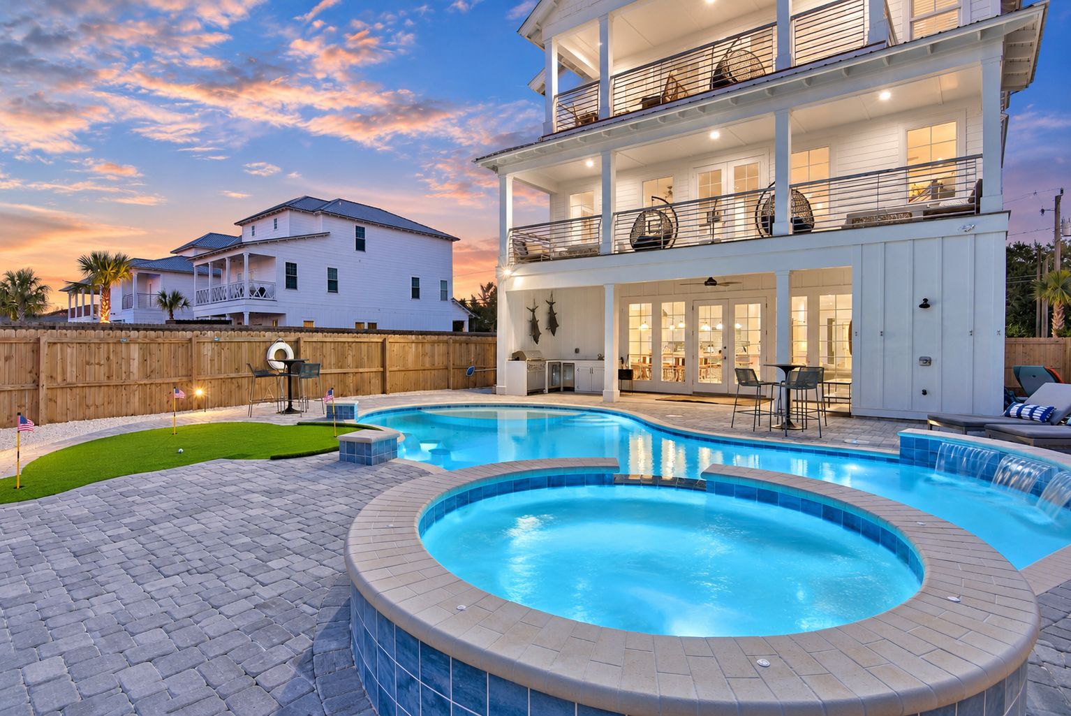 A two-story house with a swimming pool, outdoor seating, and a patio area.