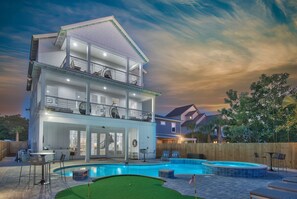 Une maison à deux étages avec une piscine, un espace salon extérieur et un jardin clôturé.