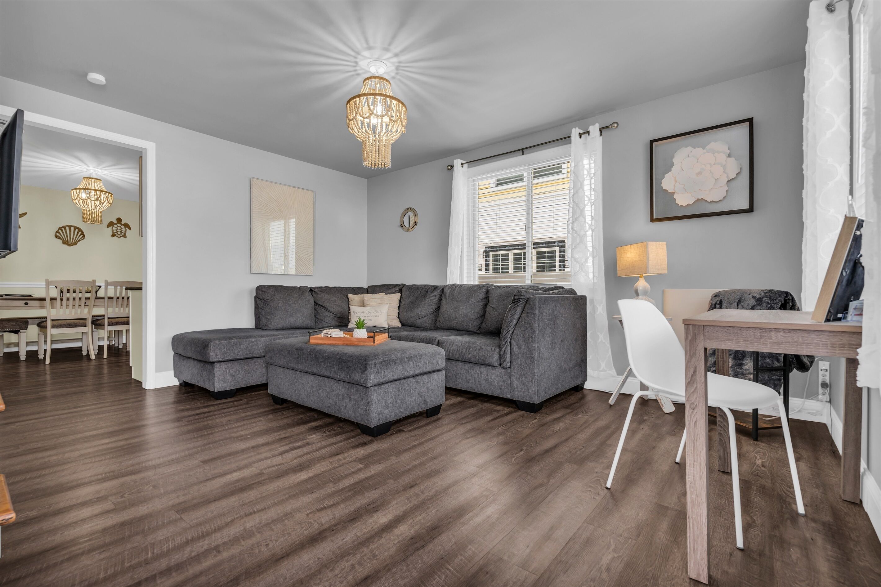 Een moderne woonkamer met een hoekbank, een houten salontafel en een kroonluchter.