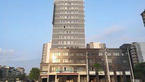 A tall, multi-story building with a modern design, featuring a prominent logo at the top. - City Comfort Inn (Jingdezhen Xinchang Road Taoxichuan) (Jingdezhen)