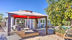 Un'area patio coperta con mobili da esterno, una piscina e un barbecue.