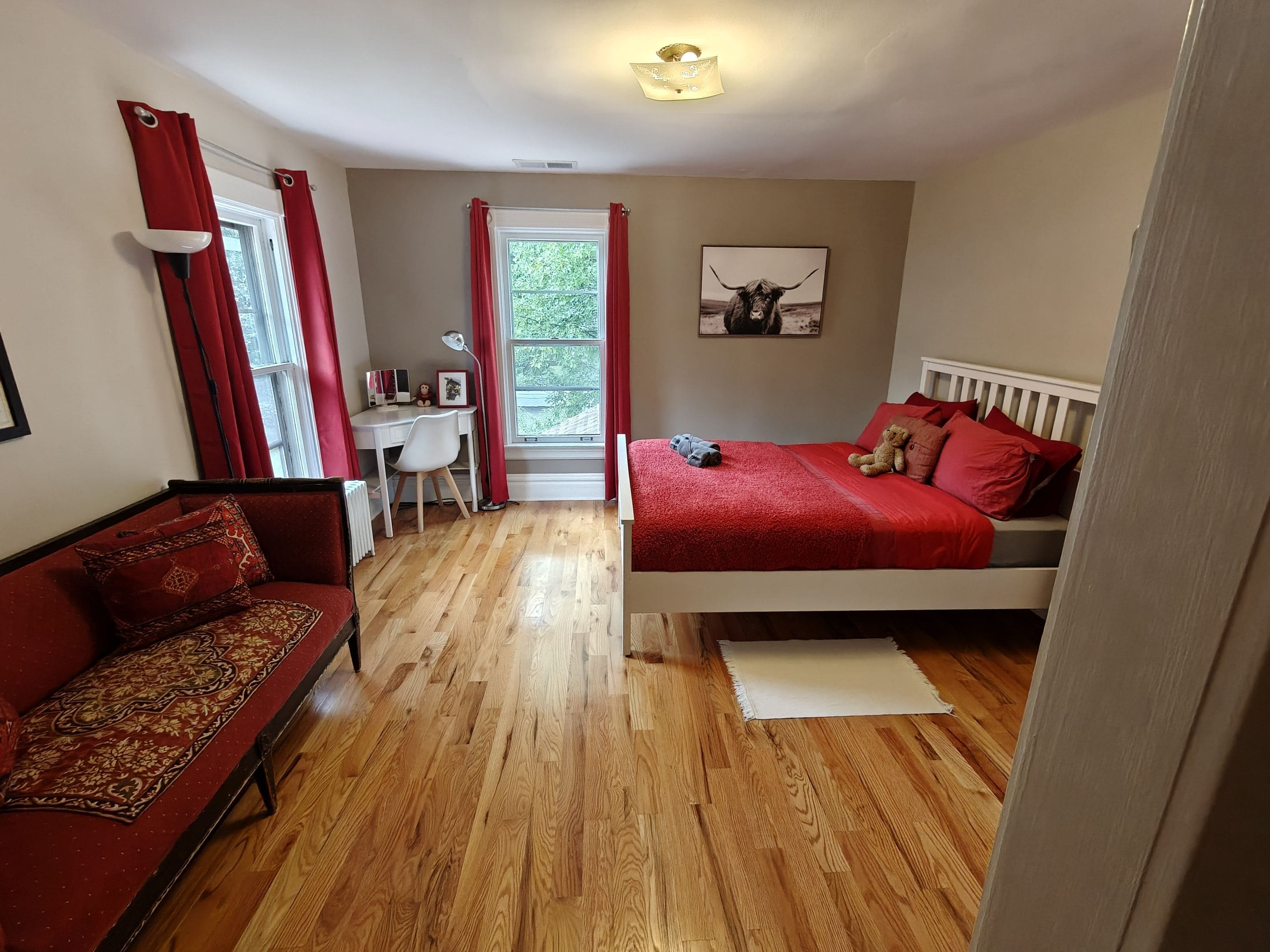 A bedroom with a bed, a desk, a chair, and a sofa.