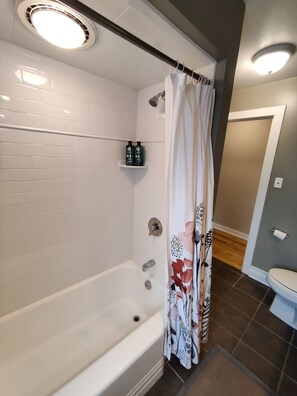 Ein Badezimmer mit Badewanne, Duschvorhang und weißen Fliesen.