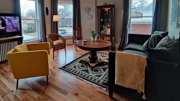 Een woonkamer met een bank, fauteuil, eettafel en televisie.