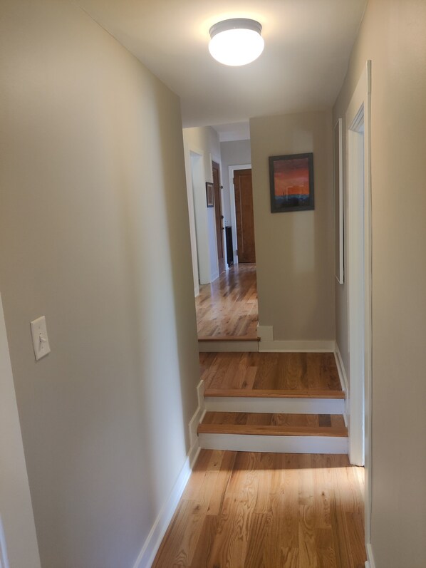 A hallway with wooden flooring, white walls, and a ceiling light. - At Home in Oak Park (Oak Park)