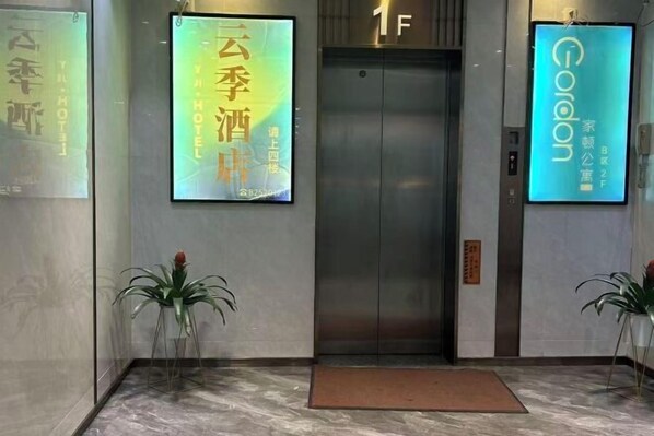 A hotel entrance with a marble floor, an elevator, and two potted plants. - Yunji Hotel (Guangzhou Olympic Sports Center Dongpu Metro Station Branch) (Guangzhou)