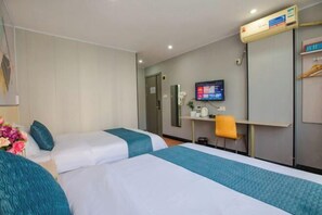 Une chambre d’hôtel avec deux lits, un bureau, une chaise, une télévision et une armoire.