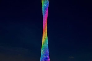 Une haute tour illuminée, dont les couleurs dégradées créent un motif visuel.