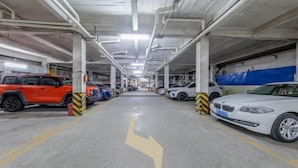 A multi-level parking garage with concrete pillars and yellow directional arrows on the floor. - Yunji Hotel (Guangzhou Olympic Sports Center Dongpu Metro Station Branch) (Guangzhou)