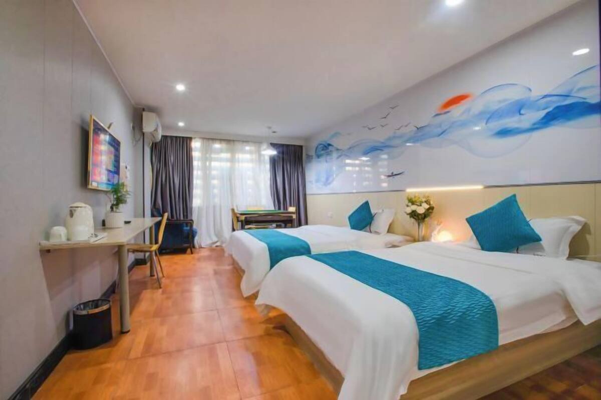 A hotel room with two beds, a desk, and a chair.