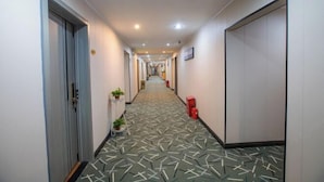 A hotel hallway with patterned carpet, doors, and a fire extinguisher. - Yunji Hotel (Guangzhou Olympic Sports Center Dongpu Metro Station Branch) (Guangzhou)