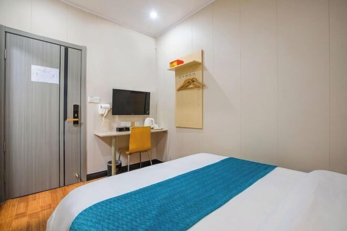 Une chambre d’hôtel comprenant un lit, un bureau avec une chaise, une télévision et une armoire.