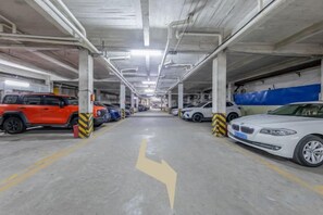 A multi-level parking garage with cars parked on multiple levels, concrete floors, and directional arrows on the ground. - Yunji Hotel (Guangzhou Olympic Sports Center Dongpu Metro Station Branch) (Guangzhou)