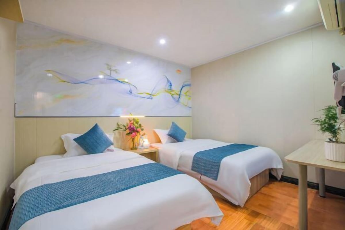 Une chambre d’hôtel avec deux lits, une petite table et une œuvre d’art murale.
