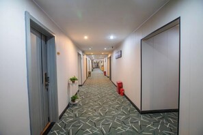 A hotel hallway with a patterned floor, doors, and a trash bin. - Yunji Hotel (Guangzhou Olympic Sports Center Dongpu Metro Station Branch) (Guangzhou)
