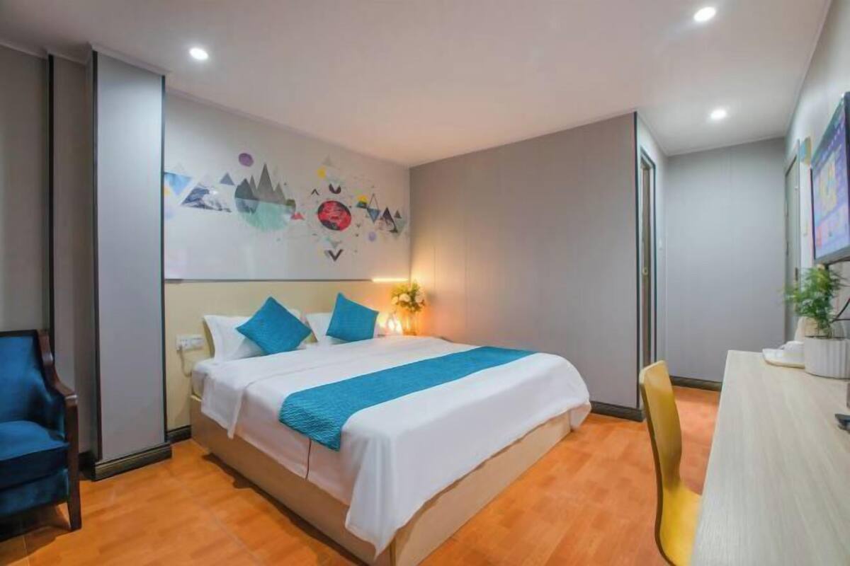 A hotel room with a bed, a desk, and a chair.