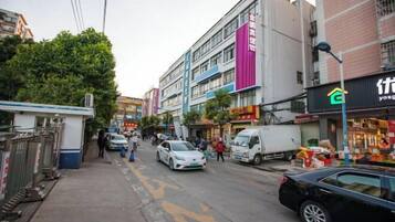 A street view with buildings, a white car, and a black car parked on the side.