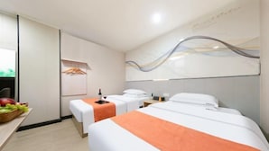 A hotel room with two beds, a fruit basket, a bottle, and a towel rack. - Yunji Hotel (Guangzhou Olympic Sports Center Dongpu Metro Station Branch) (Guangzhou)