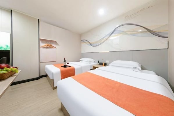 Ein Hotelzimmer mit zwei Betten, einer Obstkorb, einer Flasche und einem Handtuchhalter.