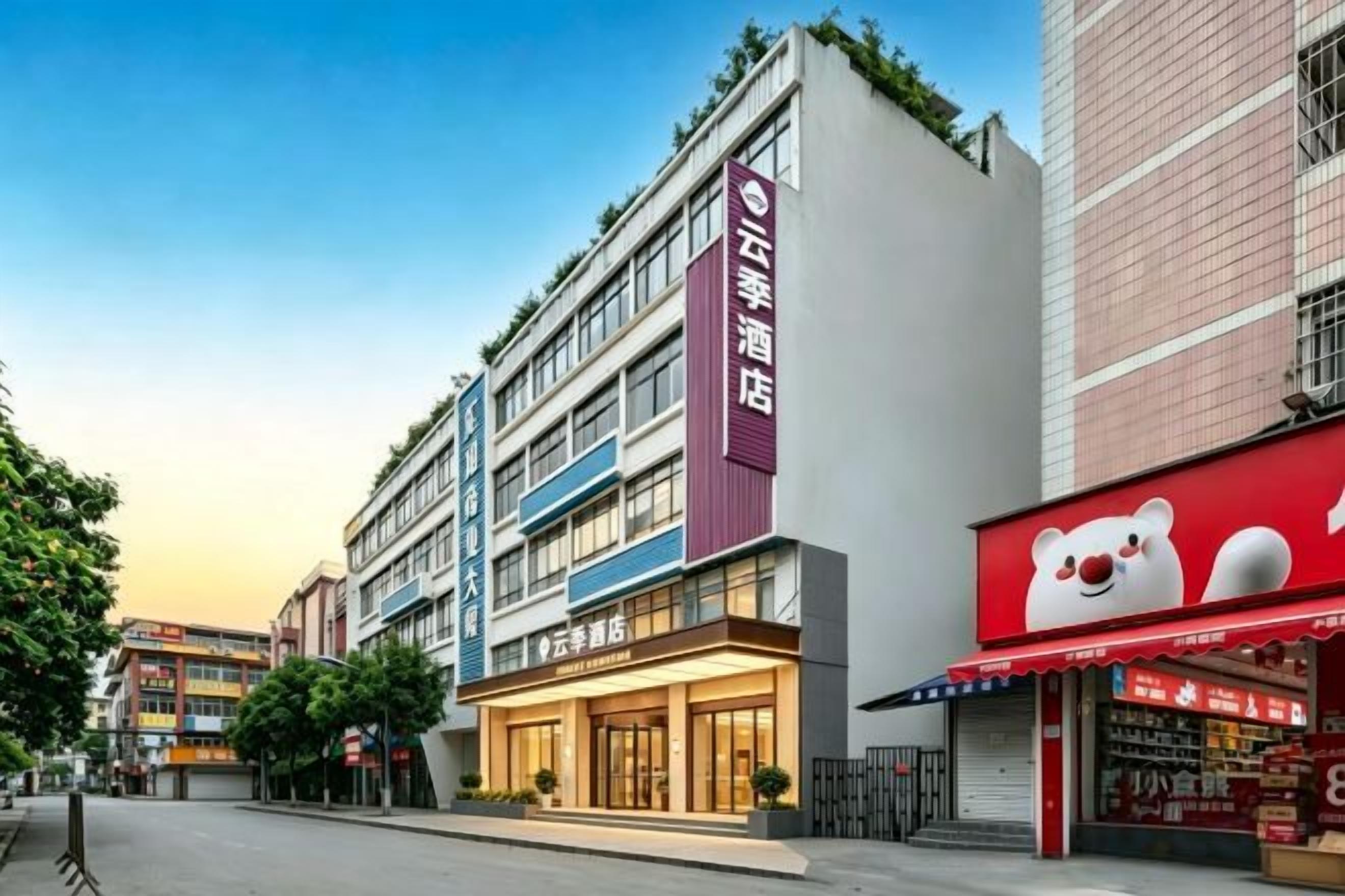 A hotel with multiple floors, a prominent red sign, and a storefront with a bear logo.