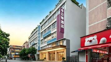 A hotel with multiple floors, a prominent red sign, and a storefront with a bear logo.
