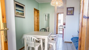 Ein Essbereich mit Tisch und Stühlen, einem Spiegel und Blick in einen anderen Raum.