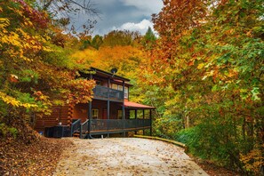 A cabin with a balcony, surrounded by autumn foliage.