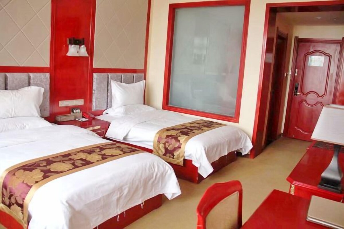 A hotel room with two beds, a desk, and a chair.