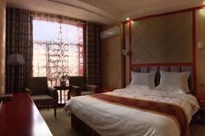 A hotel room with a large bed, two armchairs, a small table, and a desk. - Wuzhou Hotel (Yongchang)