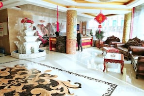 A hotel lobby with a reception desk, seating area, and decorative elements like a fountain and wall art. - Wuzhou Hotel (Yongchang)