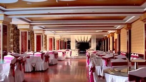 A banquet hall with rows of tables and chairs, a central aisle, and a decorative ceiling. - Wuzhou Hotel (Yongchang)