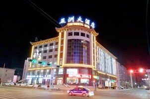 Un hotel de varios pisos con señalización iluminada, una entrada destacada y un amplio frente de cristal.