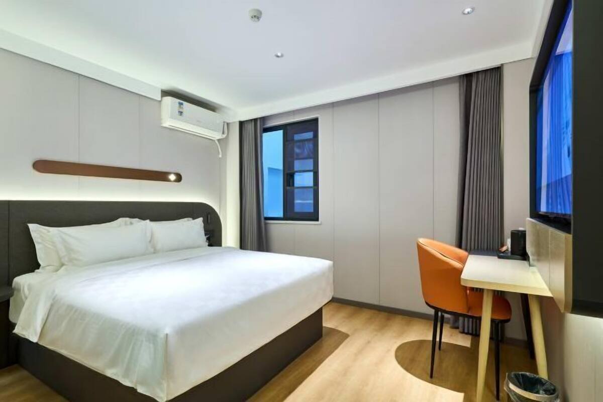 A modern hotel room with a large bed, a desk, and a chair.