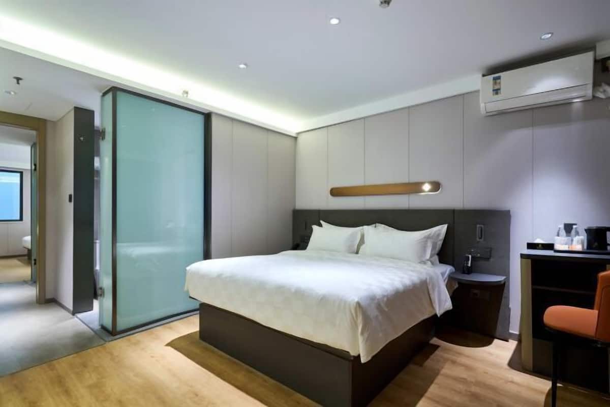 A modern hotel room with a large bed, a desk, and a chair.