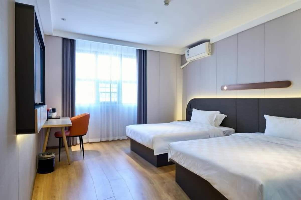 A hotel room with two beds, a desk, and a chair.